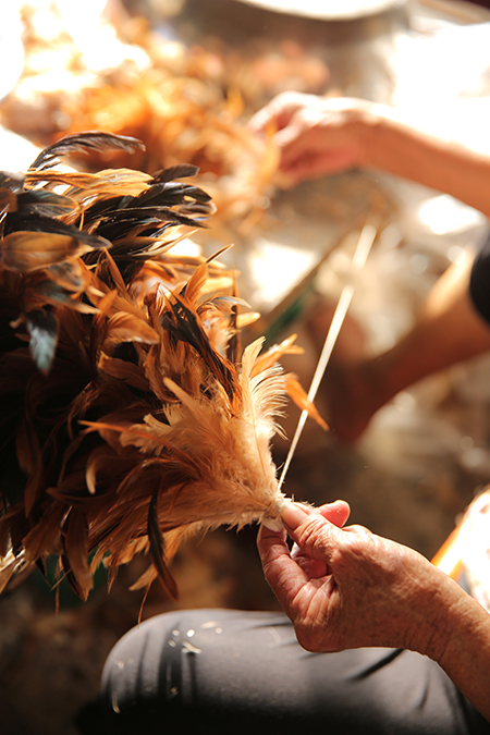 老師傅左手轉動木軸棒、右手熟練地挑撿 出合適羽毛，將雞羽一片一片黏上木棒， 同時轉動木軸，雞毛撢子逐漸在手中成形。