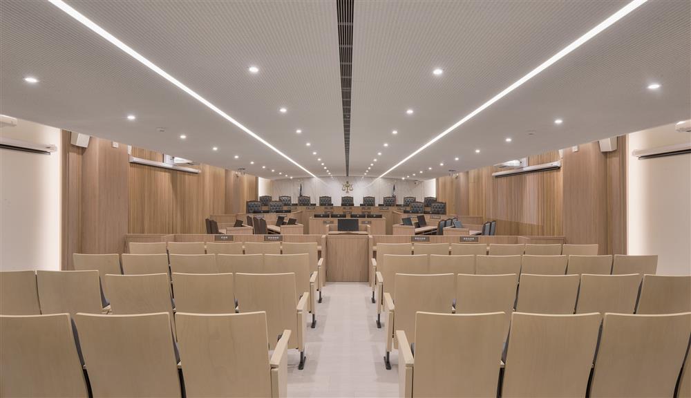 2_微弧型的天花線板從旁聽席延伸至主背牆，讓視線通向法檯，並聚焦於司法天平上，整體空間舒適沒有壓迫感_新北地院