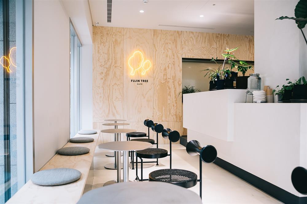 小檔富錦樹咖啡中山店以純白為主色調，裝潢設計使用溫暖木作搭配銀灰色桌椅，開放式吧檯與可容納20人的L型座位，加上店內處處可見的綠意，冷暖視覺交錯下，營造靜謐時髦氛圍，