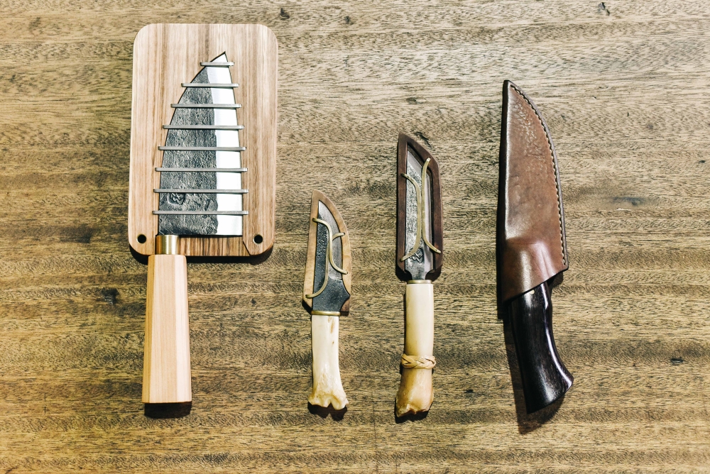 (左)因應近年盛行戶外露營,徐奕承為此設計了一款結合刀鞘與砧板的隨身刀組。(左2)處理獸皮用的「獸皮剝製刀」。(右2)排灣族分肉刀。刀柄上的藤編也是徐奕承所編。兩刀柄都是羊腿骨。(右) 是徐奕承早期製作較多歐美風格的小獵刀,也有客人會訂製蒐藏。並以皮革作為刀鞘。 (左)因應近年盛行戶外露營,徐奕承為此設計了一款結合刀鞘與砧板的隨身刀組。(左2)處理獸皮用的「獸皮剝製刀」。(右2)排灣族分肉刀。刀柄上的藤編也是徐奕承所編。兩刀柄都是羊腿骨。(右) 是徐奕承早期製作較多歐美風格的小獵刀,也有客人會訂製蒐藏。並以皮革作為刀鞘。