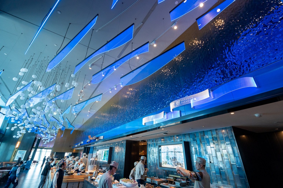 小檔饗 A Joy【圖3-2】「饗 A Joy」整體空間設計上，結合台灣地貌並納入文化意涵，打造「山」、「海」、「原」、「城」四區境向，打造沉浸式台灣尋味之旅。(圖為：饗 A Joy海境裝置藝術「粼粼海之流」)抬頭看便是波浪與氣泡，湛藍流動於空間氛圍，牆面金屬漸層鍍色更有海平面曙光的意象。