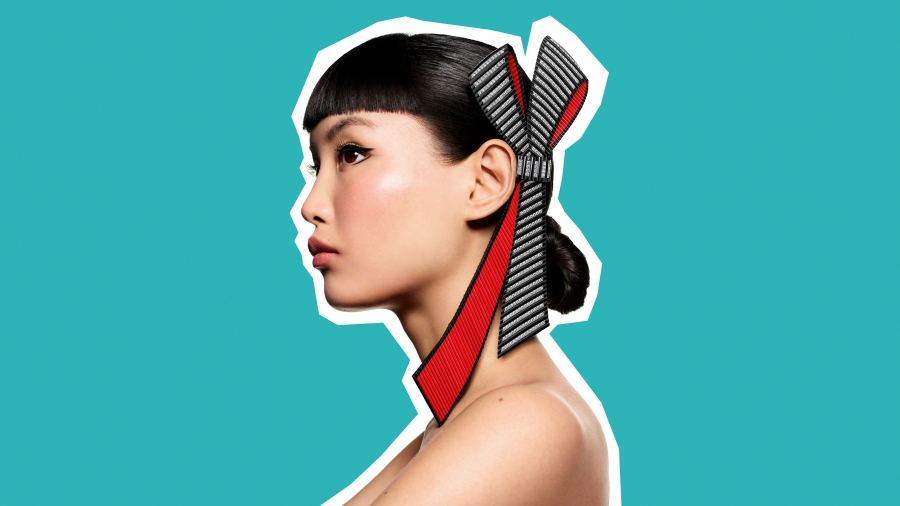 Tie the Knot 點綴於如雲秀髮上的碩大蝴蝶結，一側火紅如焰， 另一側則裝飾形似品牌經典元素羅緞直線刻紋(Grosgrain)的黑白條紋。柔軟如絲，似要隨風拂動。