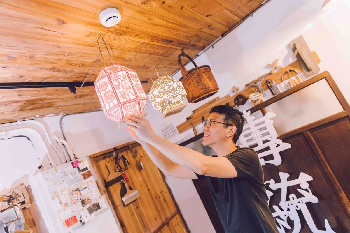 陳治旭開心地注視天花板上懸掛的紙雕燈籠，臉上帶著專注又愉悅的笑容。（圖片來源：《生活工藝誌》第十二期）