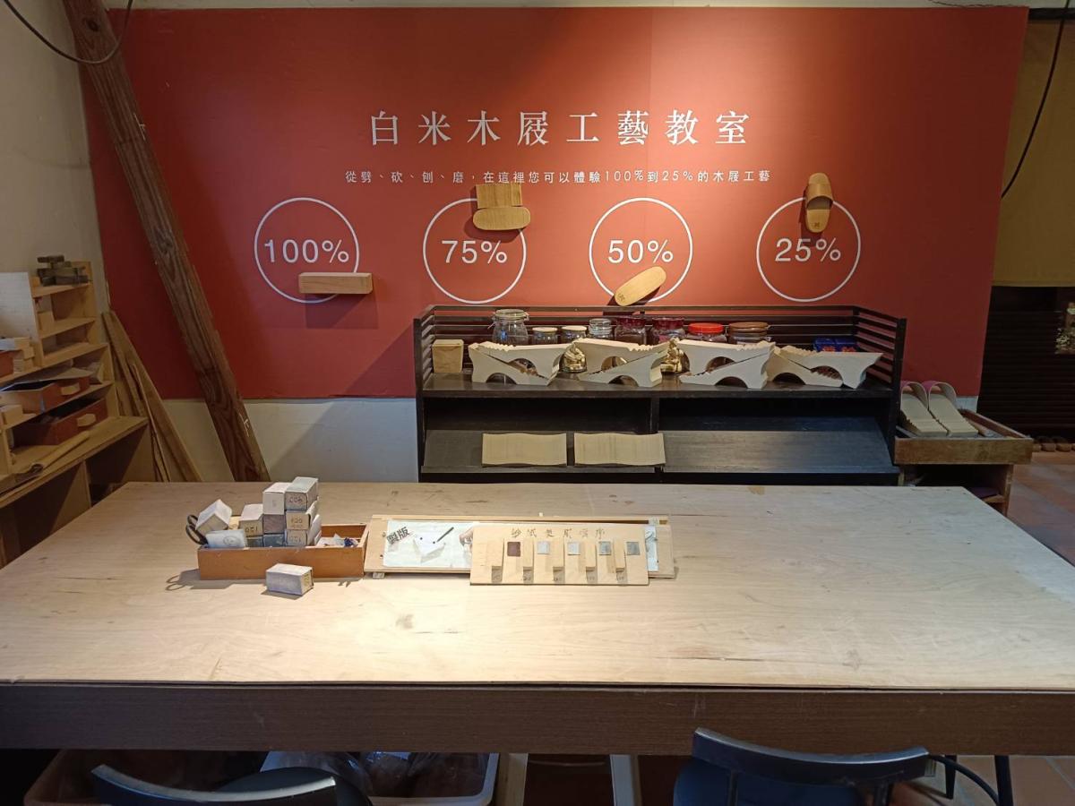 在白米木屐館的工房教室，長桌上擺放著木作樣品和工具，牆面以資料圖表展現工坊理念，營造出專業且溫馨的手作氛圍。（圖片提供：白米木屐館）