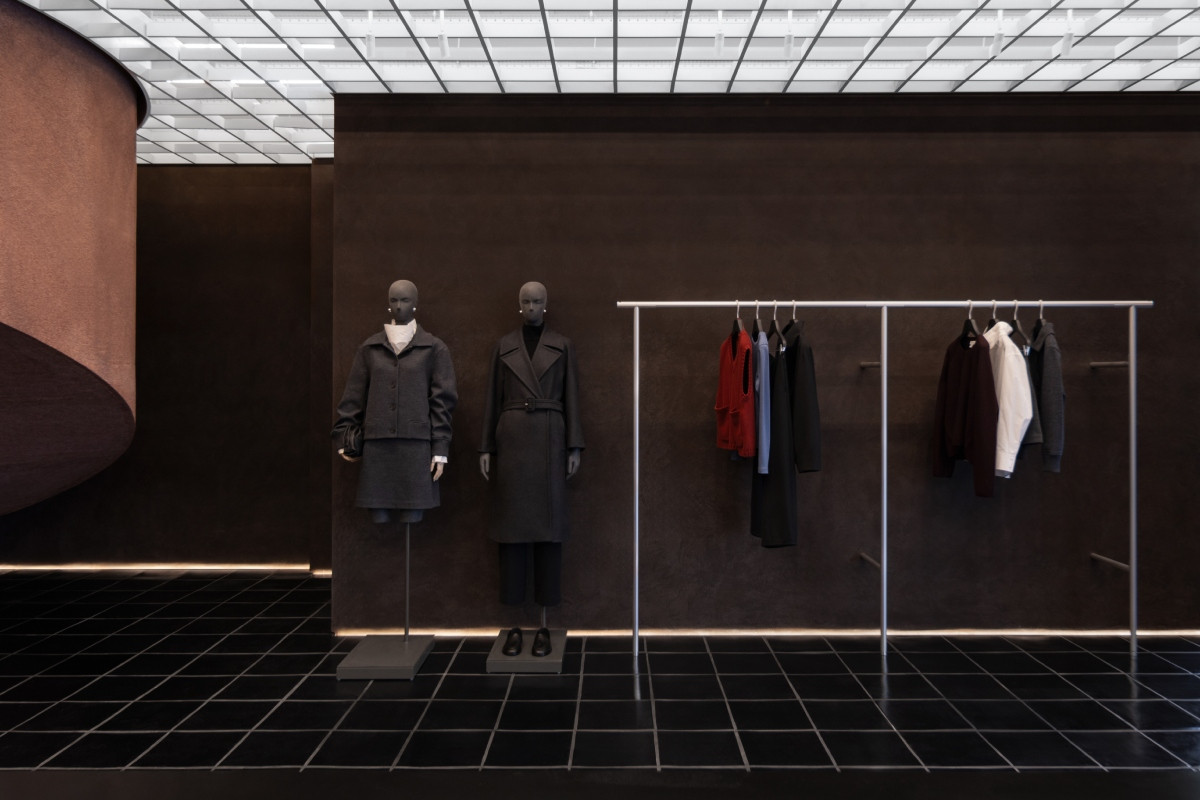 一樓展售空間；地面鋪設黑磚，四周設有鋁製衣桿陳列女裝。（圖片提供：COS）