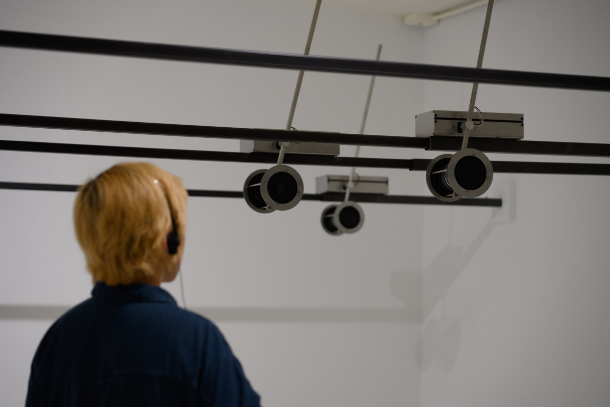 陳庭榕〈以他們之名〉∣臺灣CHEN Ting-Jung, Of Their Signs 2025 時間性媒體 （10 聲道聲音系統與單體喇叭、4聲道感應式聲音系統與接收器耳機、銅圈、電力、網路訊號接收器與發射器、金屬、黑色玻璃、白色地 毯 1971-2025 聯合國針對領土爭議之演講） 18 min 20 s 藝術家提供