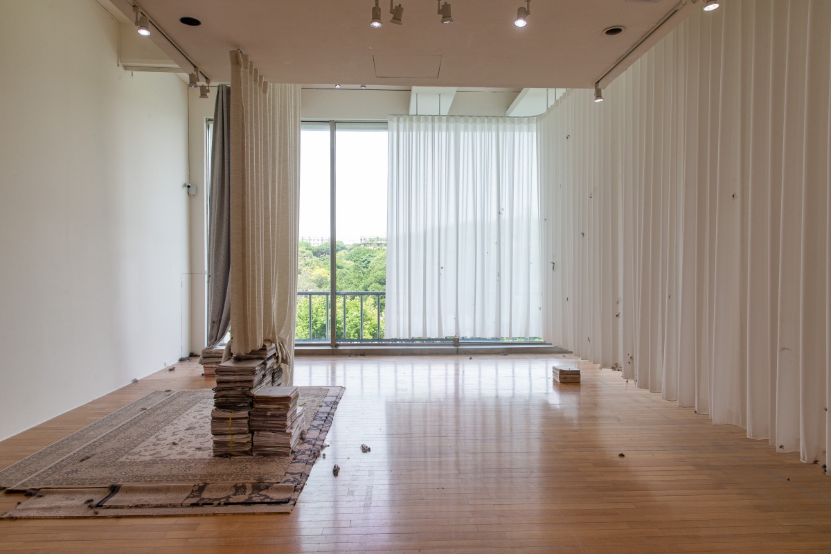 湯雅雯，《揚起》，2023-2026，循環扇、格柵出風口、蛇形簾、灰塵、再生棉、地毯、白報紙、毛線，尺寸依場地而定。藝術家自藏。（圖片提供：北美館）