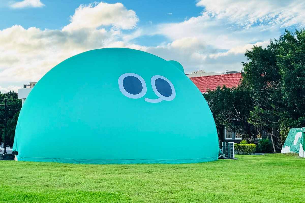 展覽期間「巨大a-We」空降空總國家文化基地東草坪。原有穹頂劇場化身為高達17公尺的巨型 a-We，以Q彈並充滿韌性的氣泡造型，成為園區最醒目的拍照打卡地標 。（圖片來源：文化部）